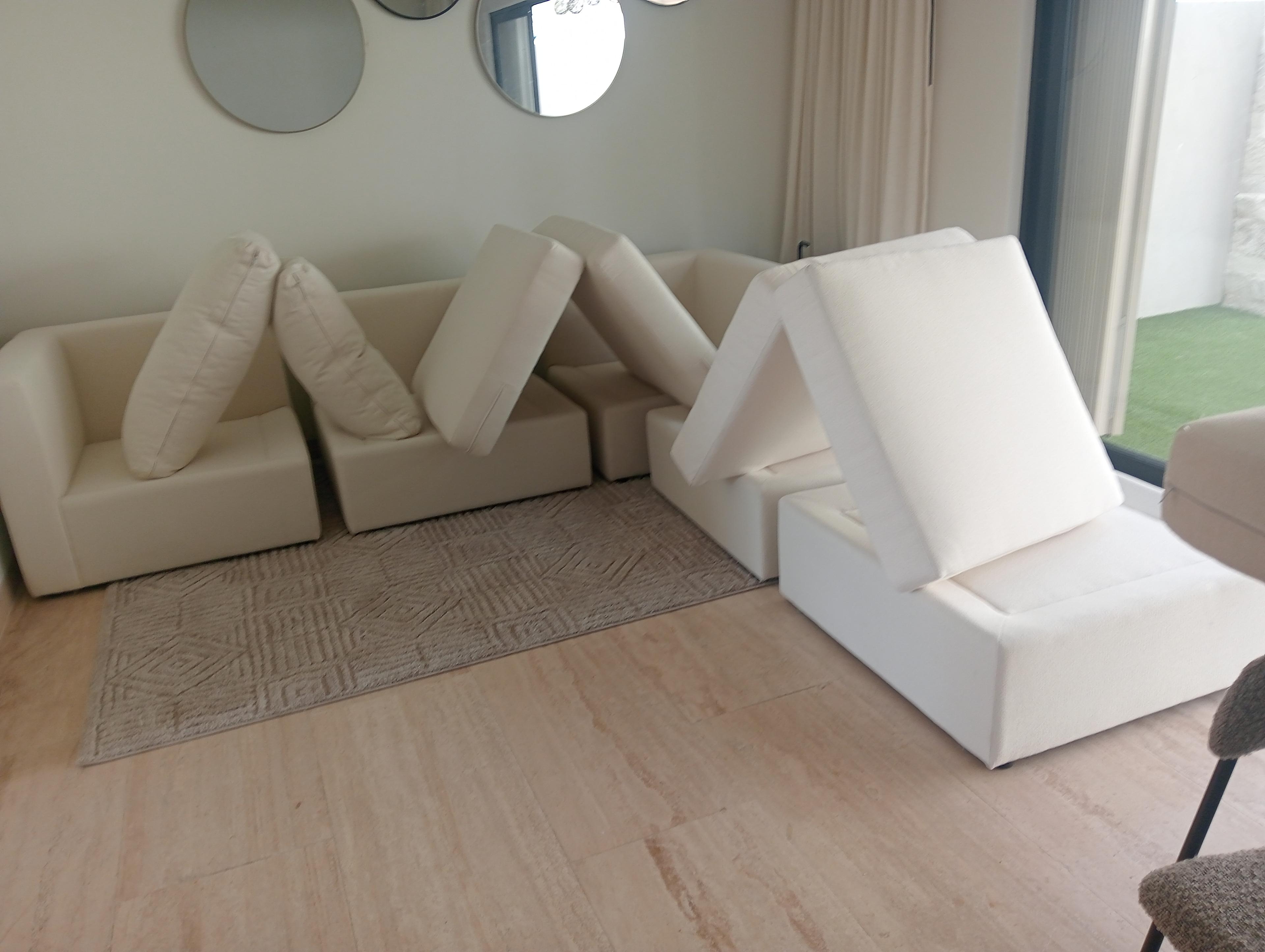 Sillones blancos con cojines levantados en una sala moderna con espejos circulares en la pared.